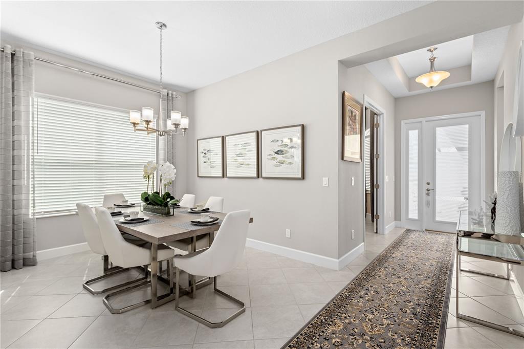 A dining room with a table, white chairs, and a hallway leading to the front door — 4839 SEVILLA SHORES DRIVE, WIMAUMA, FL