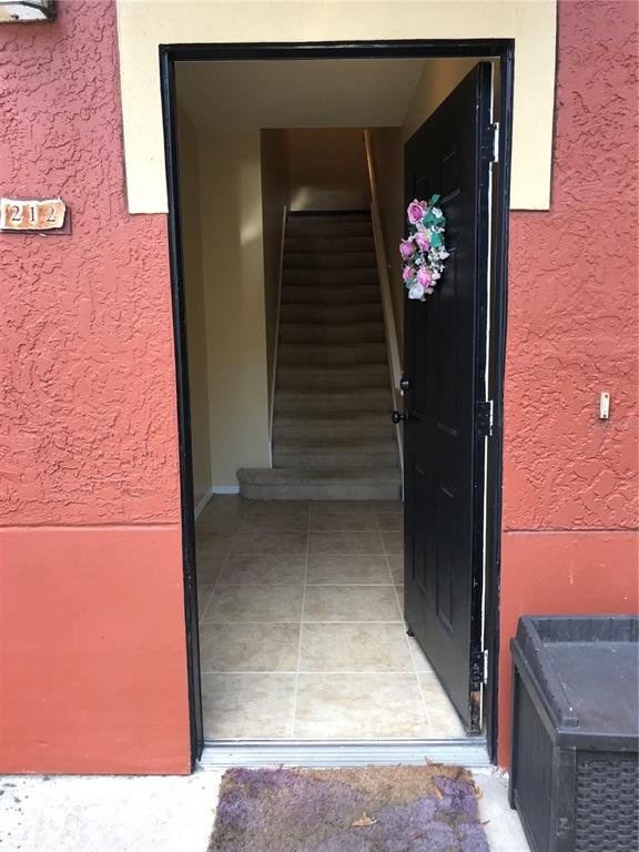 A black front door with a floral wreath sits beside a garage entrance — 180 VILLA DI ESTE TERRACE UNIT 212, LAKE MARY, FL