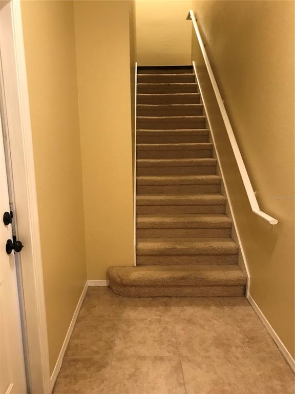 A small entryway with yellow walls, tile flooring, a front door, and an interior door — 180 VILLA DI ESTE TERRACE UNIT 212, LAKE MARY, FL