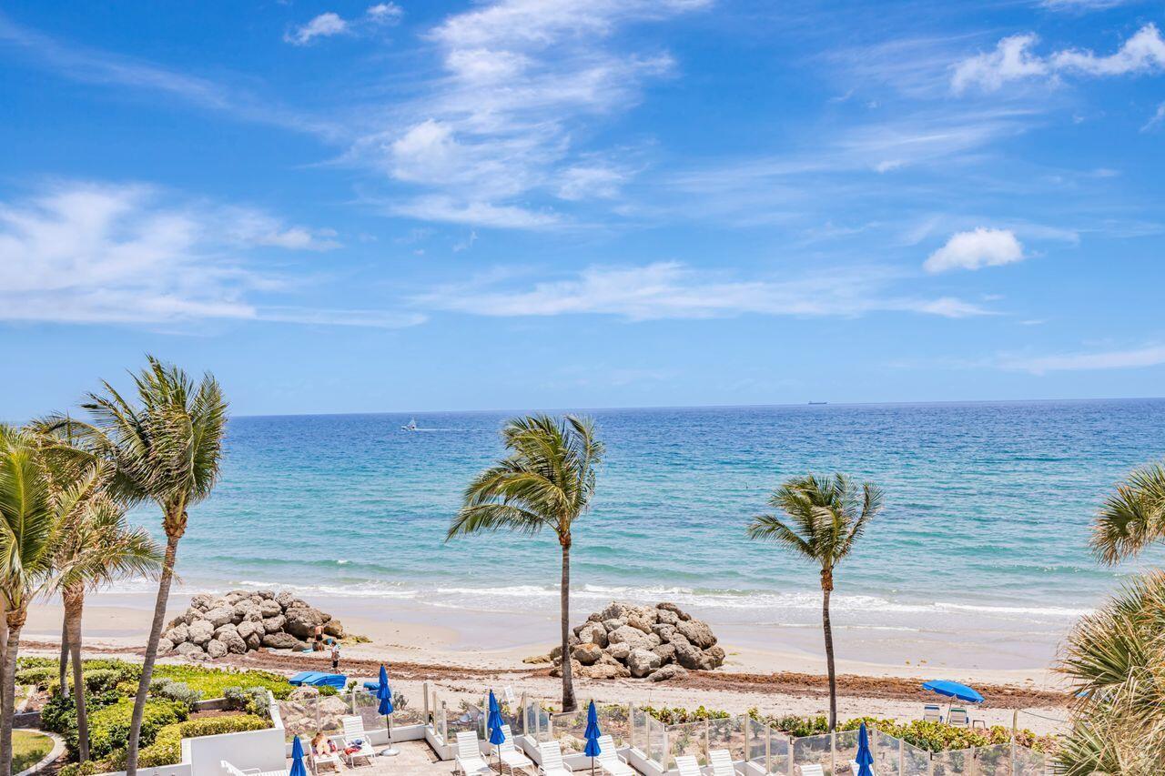 A view of a sandy beach and ocean from a balcony with palm trees — 500 SE 21st Avenue # 403, Deerfield Beach FL 33441, DEERFIELD BEACH, FL