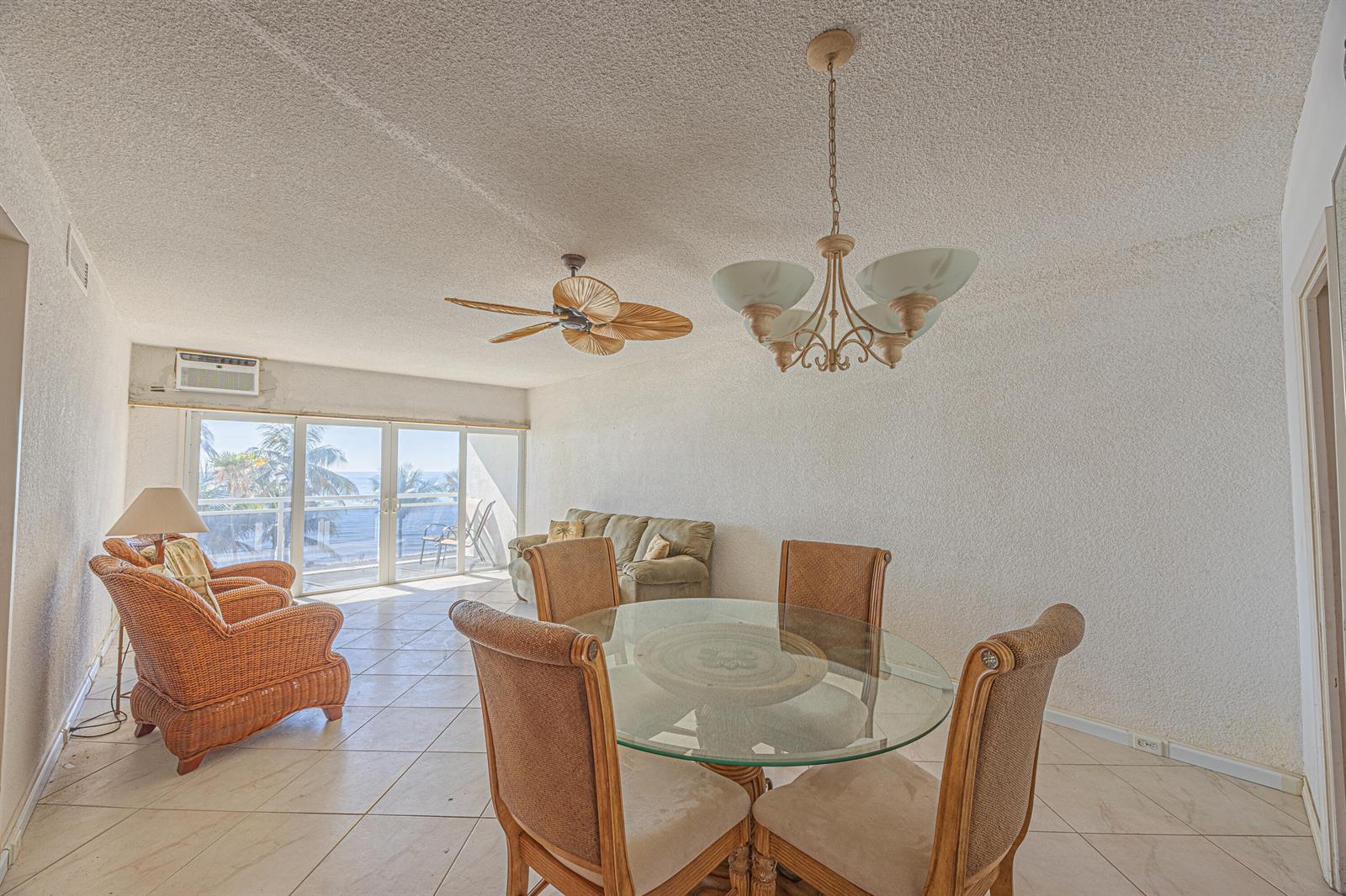 A living and dining area features tile floors, a glass table, and a balcony view — 500 SE 21st Avenue # 403, Deerfield Beach FL 33441, DEERFIELD BEACH, FL