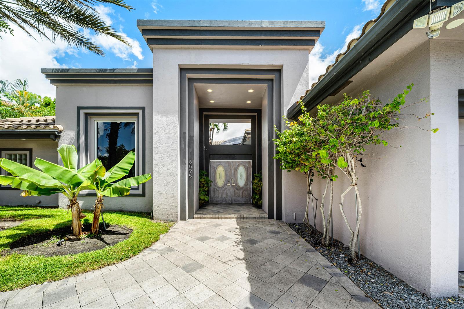 The exterior of a house features a paved walkway leading to a double-door entryway — 6595 NW 32nd Terrace, Boca Raton FL 33496, BOCA RATON, FL