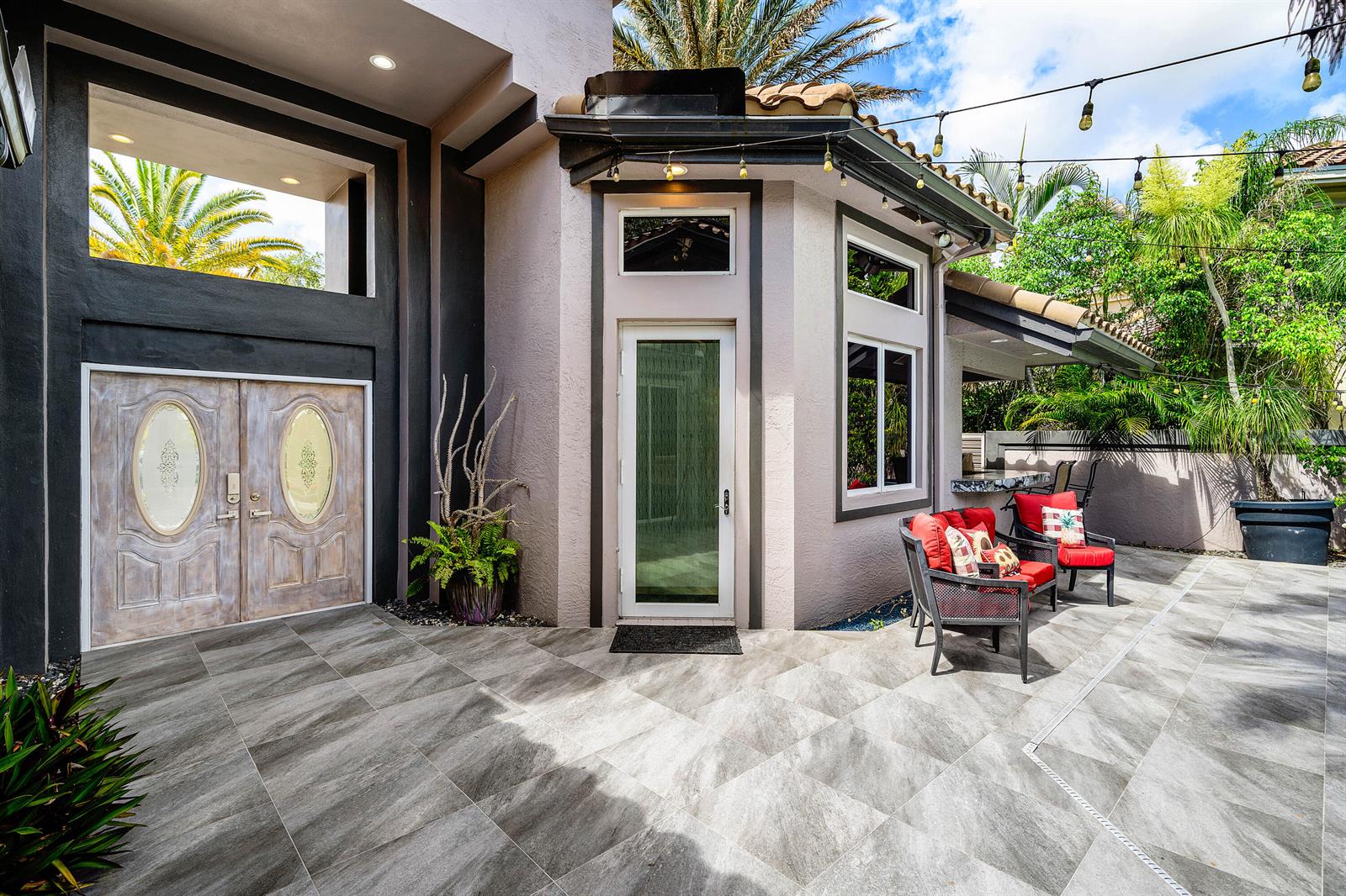 A patio features gray tiled flooring, outdoor seating with red cushions, and string lights overhead — 6595 NW 32nd Terrace, Boca Raton FL 33496, BOCA RATON, FL