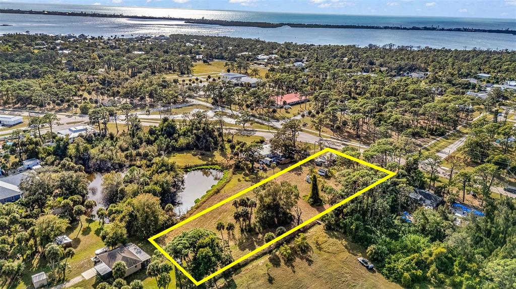 An aerial view shows a rectangular plot of land outlined in yellow near a pond — 787 OLD ENGLEWOOD ROAD, ENGLEWOOD, FL