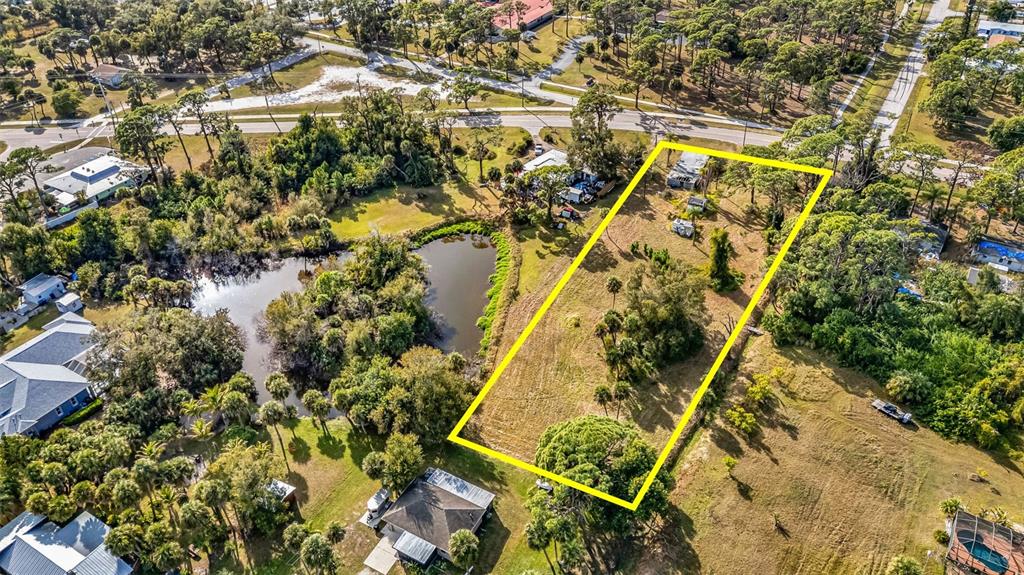 An aerial view shows a rectangular vacant lot outlined in yellow next to a pond — 787 OLD ENGLEWOOD ROAD, ENGLEWOOD, FL