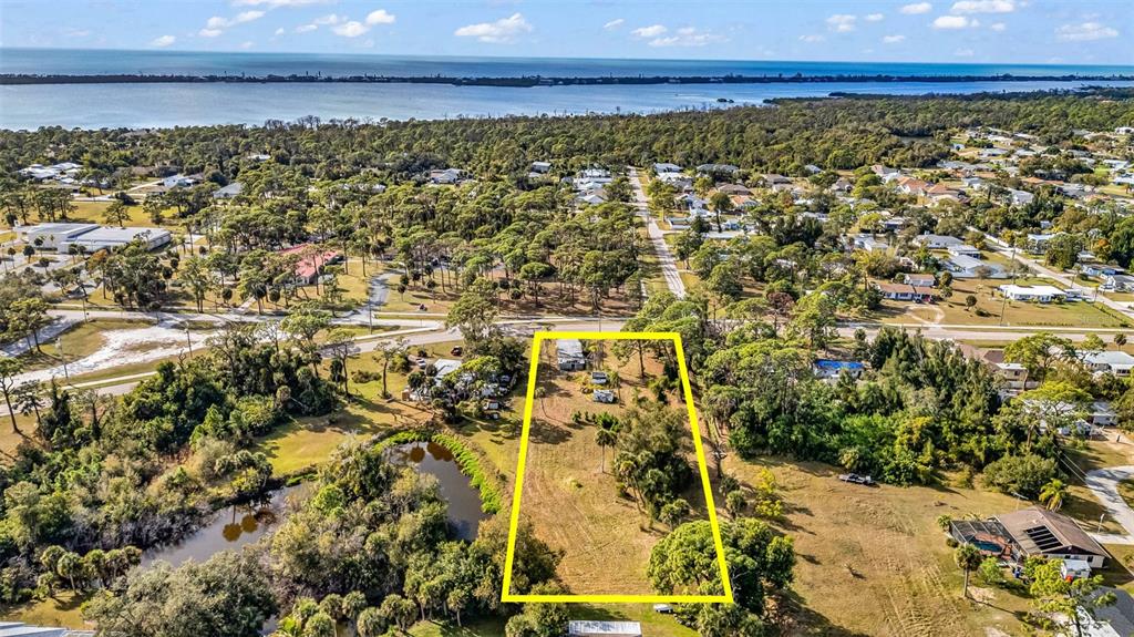 An aerial view shows a rectangular plot of land outlined in yellow near a body of water — 787 OLD ENGLEWOOD ROAD, ENGLEWOOD, FL
