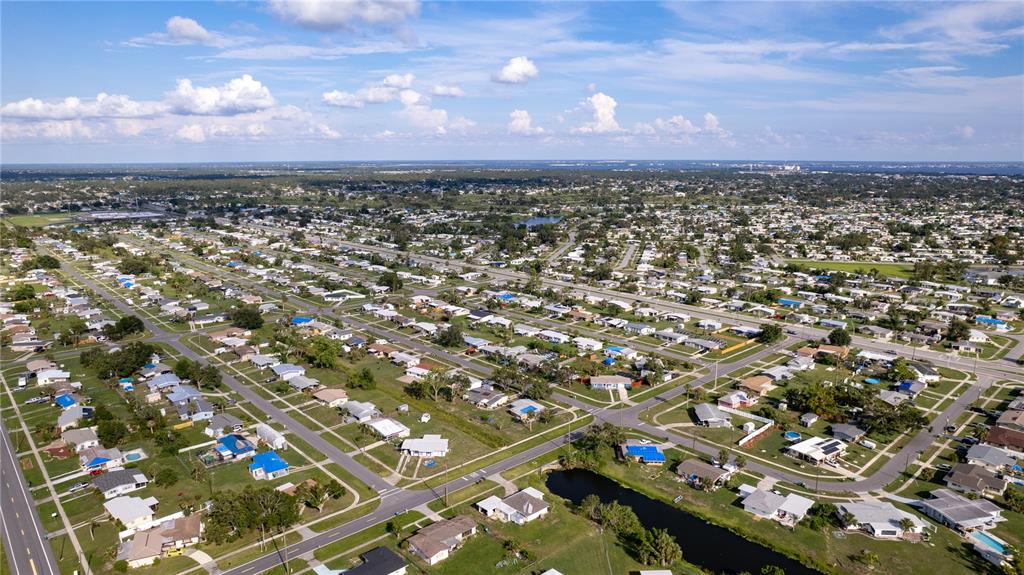 An aerial view shows a dense residential neighborhood with many single-story homes and a canal — 1556 BIRCHCREST BOULEVARD, PORT CHARLOTTE, FL