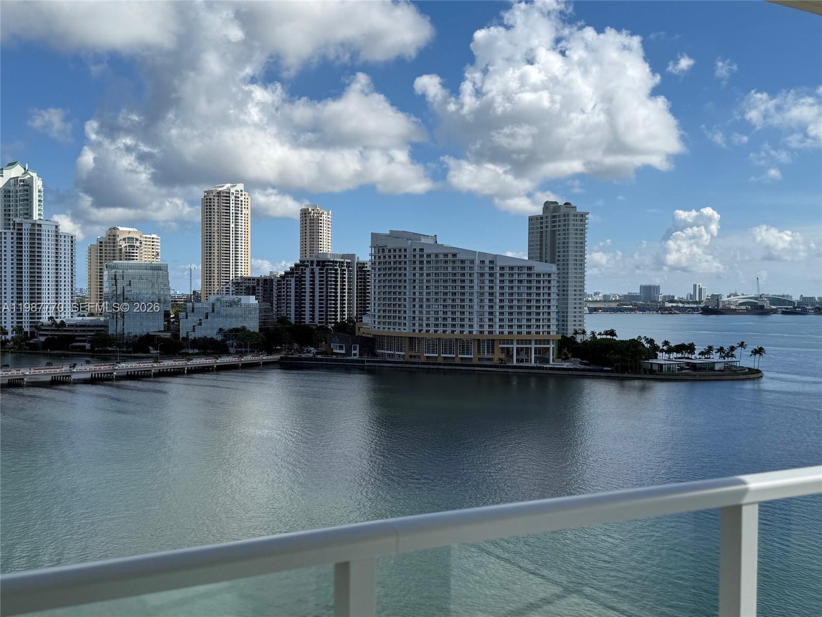 A high-angle view of a waterfront cityscape with multiple skyscrapers under a cloudy blue sky — 1155 Brickell Bay Dr # 1008, Miami FL 33131, MIAMI, FL