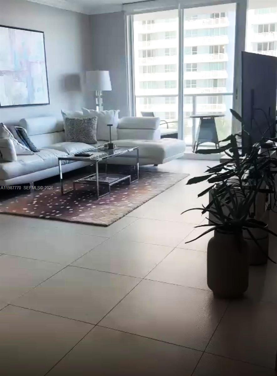A modern living room features a white sectional sofa, a glass coffee table, and tile flooring — 1155 Brickell Bay Dr # 1008, Miami FL 33131, MIAMI, FL