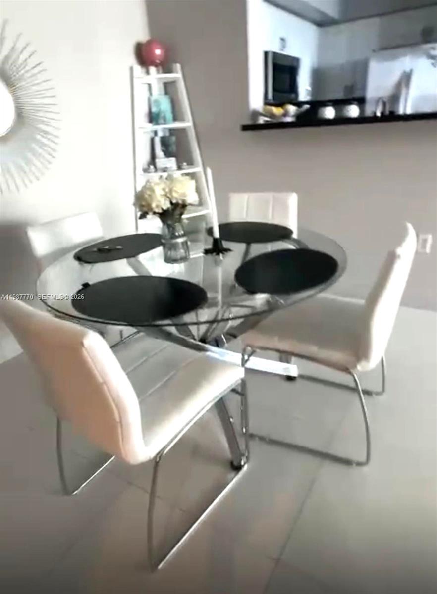 A glass-topped dining table with four white chairs sits in a bright room — 1155 Brickell Bay Dr # 1008, Miami FL 33131, MIAMI, FL