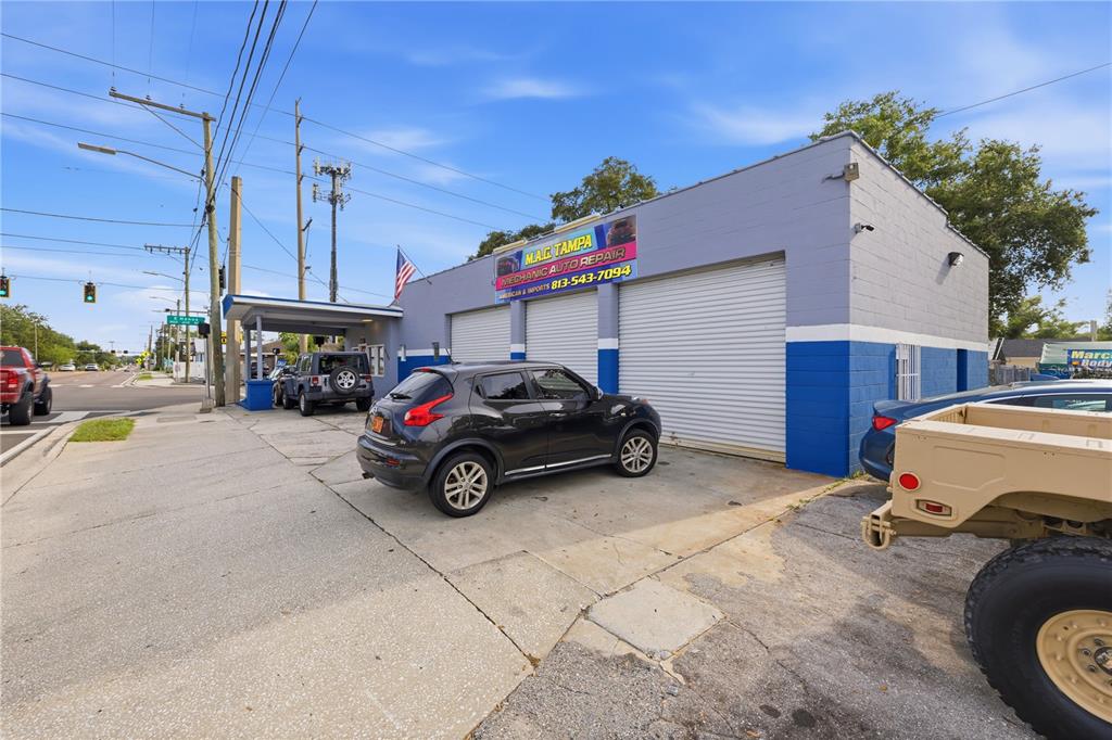An exterior view of an auto repair shop with two garage bays and parked vehicles — 6200 N NEBRASKA AVENUE, TAMPA, FL