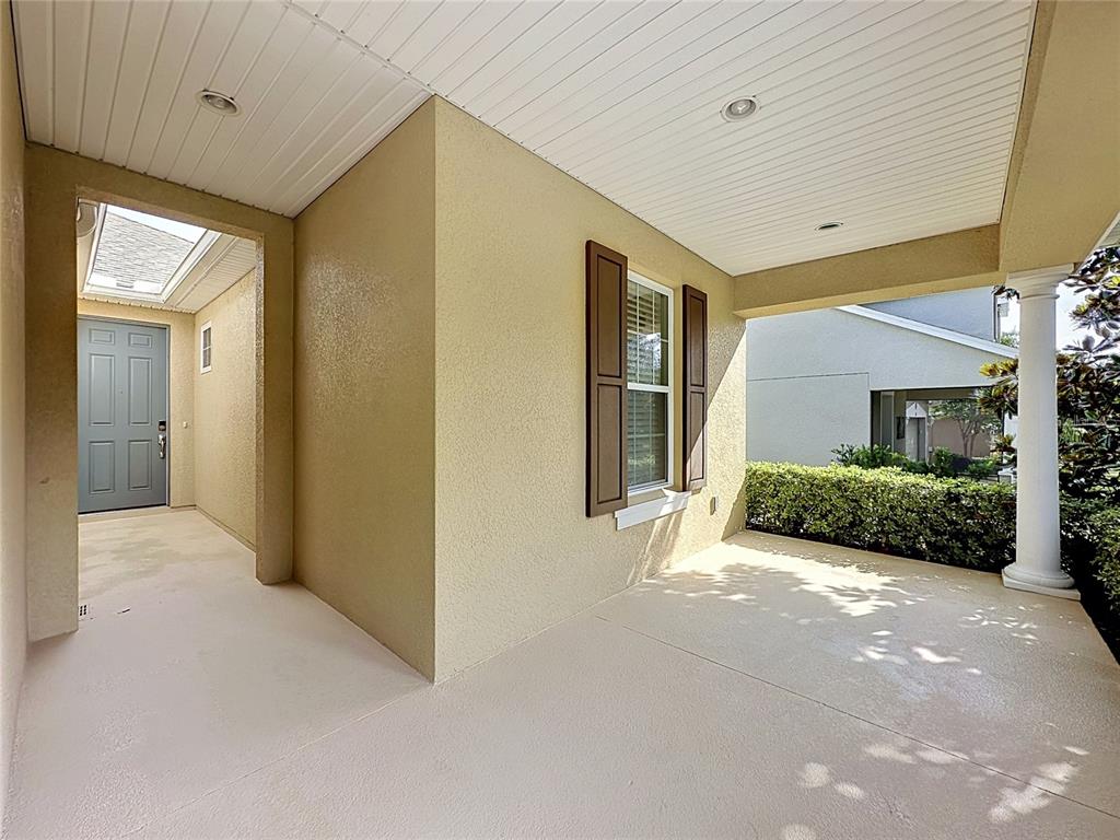 A covered front porch with a light-colored concrete floor, a gray door, and a column — 395 SILVER MAPLE ROAD, GROVELAND, FL