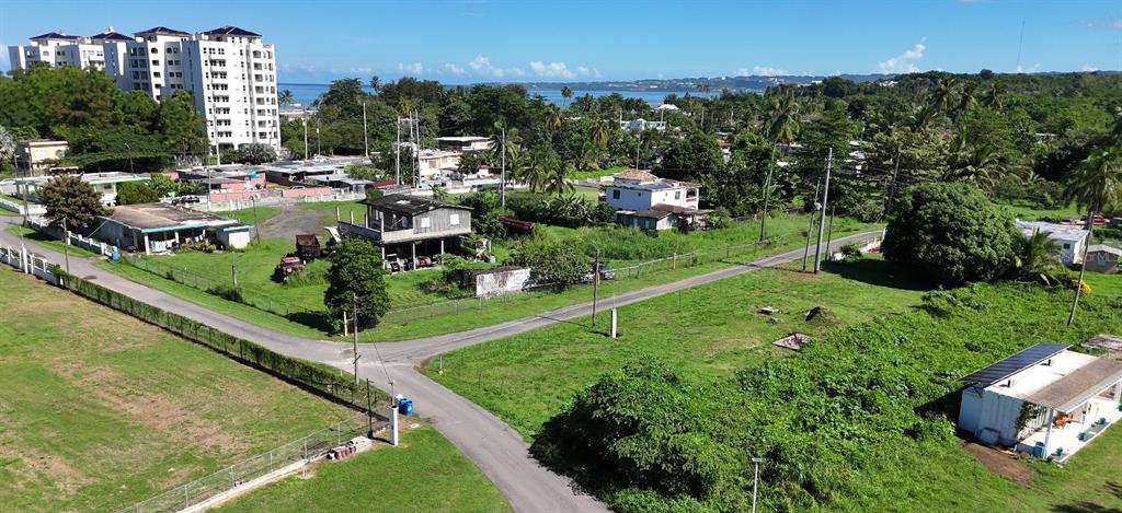 An aerial view shows a residential neighborhood with houses, a road, and a large building — km 19.9 Int CARRETERA 115 SOLAR #4, AGUADA, PR