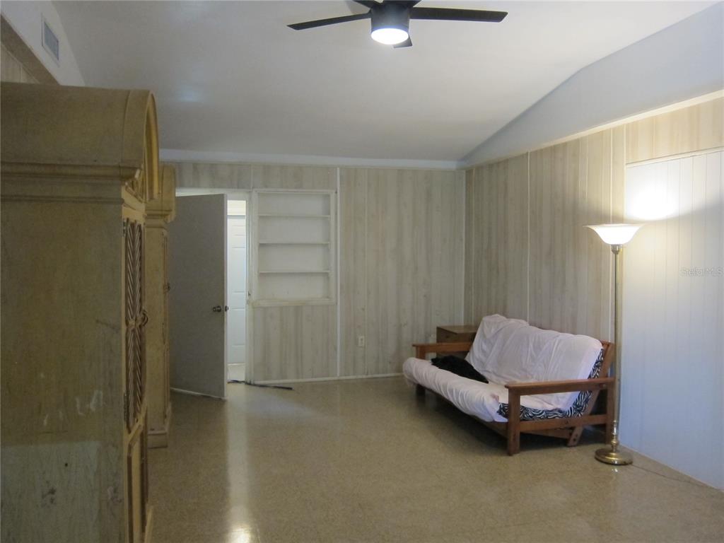 A living room features wood-paneled walls, a futon, a floor lamp, and a ceiling fan — 1602 SW WILLISTON ROAD UNIT A, GAINESVILLE, FL