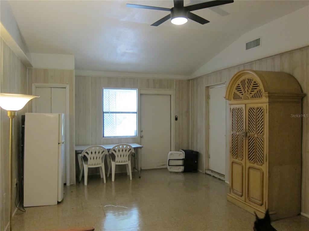 A room with wood-paneled walls, a ceiling fan, a refrigerator, and a large armoire — 1602 SW WILLISTON ROAD UNIT A, GAINESVILLE, FL