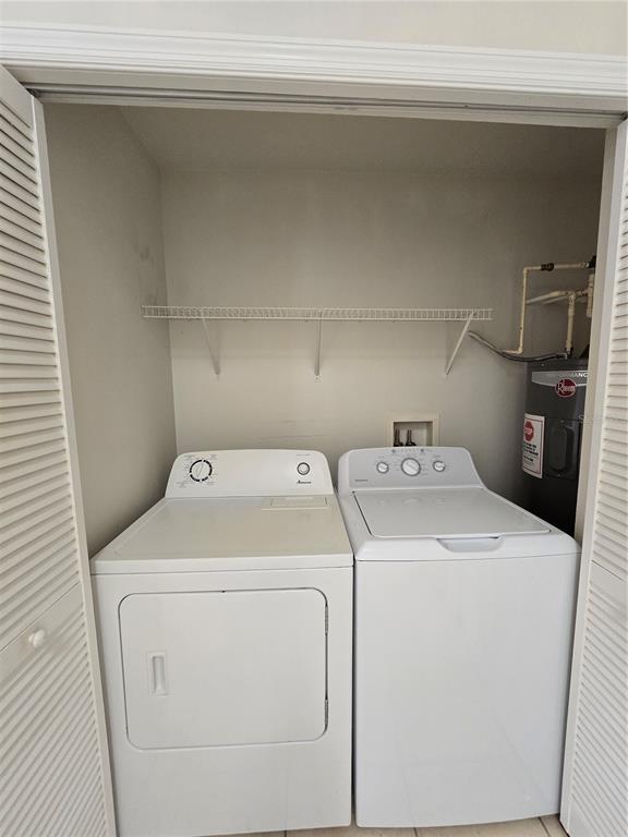 A laundry closet contains a white washer and dryer next to a water heater — 2790 CLUB CORTILE CIRCLE UNIT B, KISSIMMEE, FL