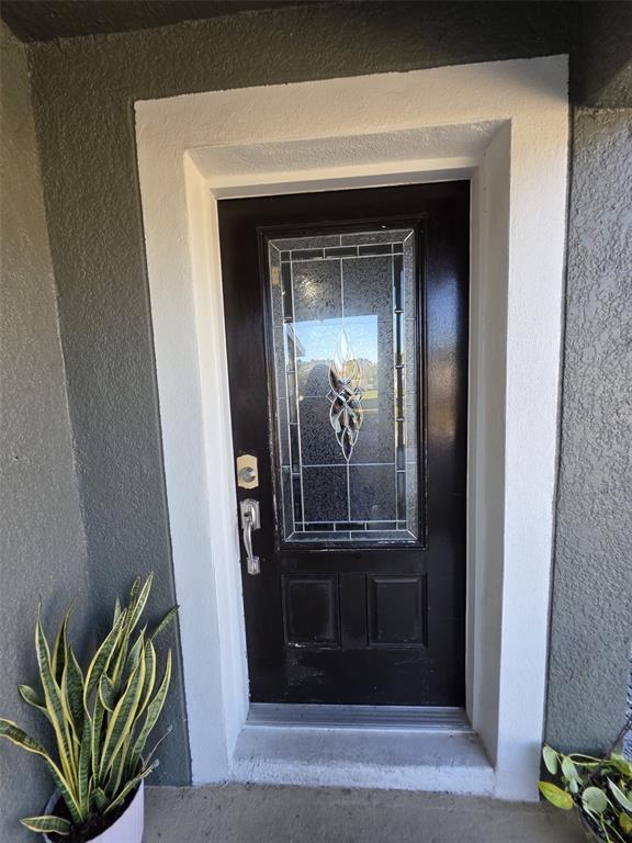 A black front door with a decorative glass insert is framed by white trim — 600 GEORGIA AVENUE, ST CLOUD, FL