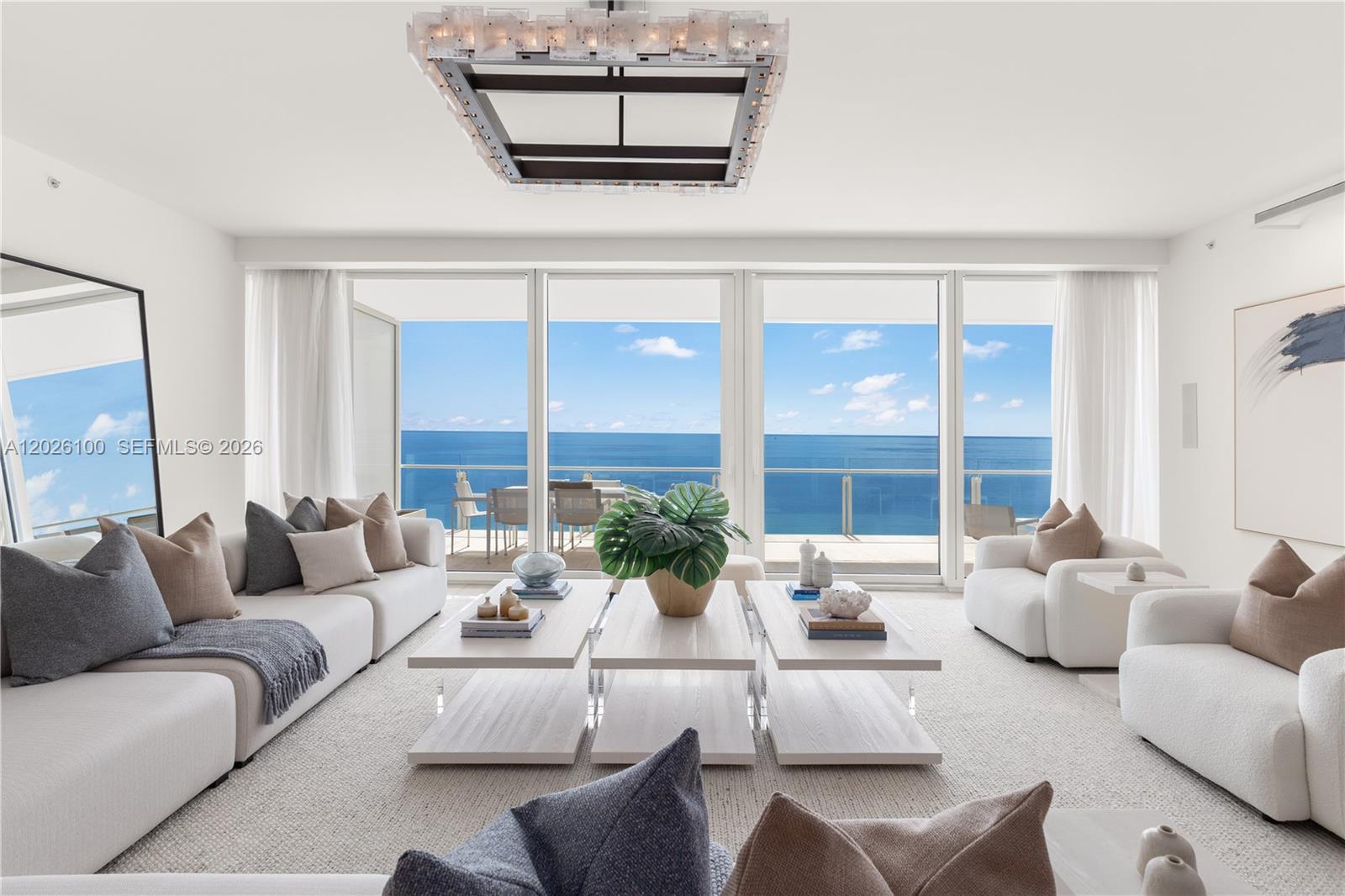 A bright living room features white furniture, three tiered coffee tables, and floor-to-ceiling ocean views — 9001 Collins Ave # 1003, Surfside FL 33154, SURFSIDE, FL