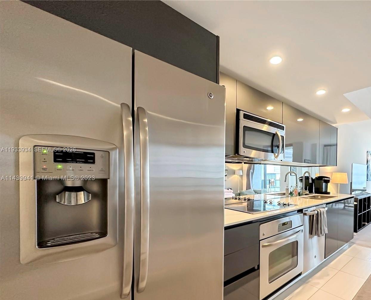 A modern kitchen features stainless steel appliances, dark cabinetry, and white countertops — 31 SE 6th St # 703, Miami FL 33131, MIAMI, FL