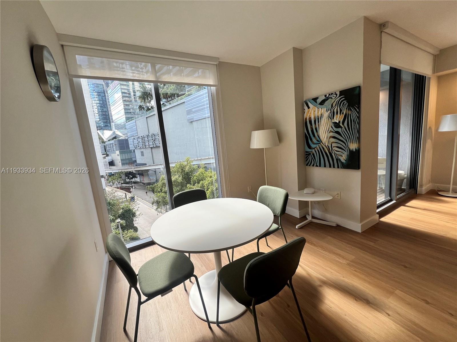 A dining area features a round white table, four green chairs, and city views — 31 SE 6th St # 703, Miami FL 33131, MIAMI, FL
