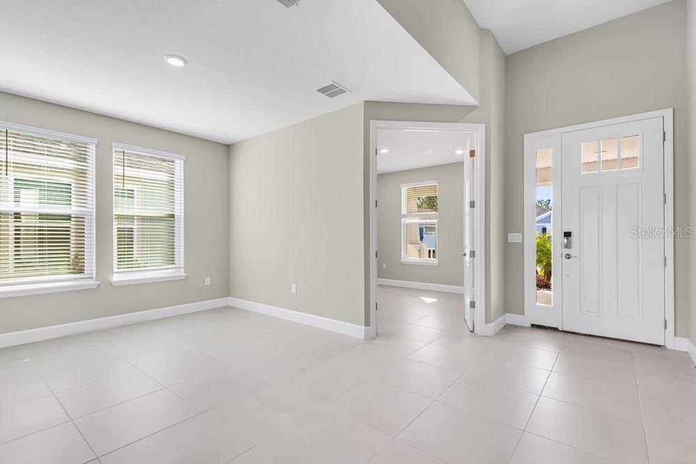 A bright room with light gray walls, white tile floors, and a white front door — 10 GEOSAM DRIVE, PALM COAST, FL