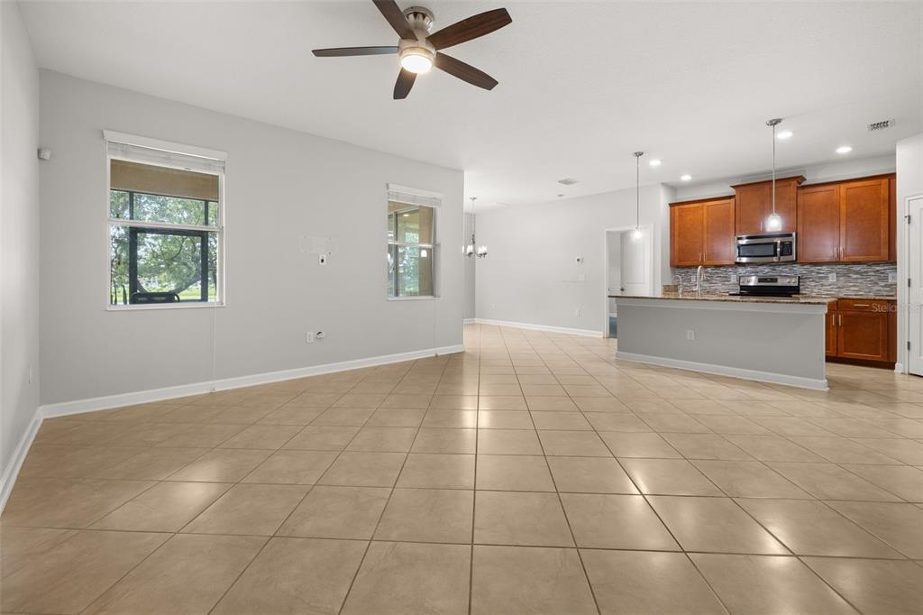 An open-concept living area with tile flooring, a ceiling fan, and an adjacent kitchen — 14157 GOLD BRIDGE DRIVE, ORLANDO, FL