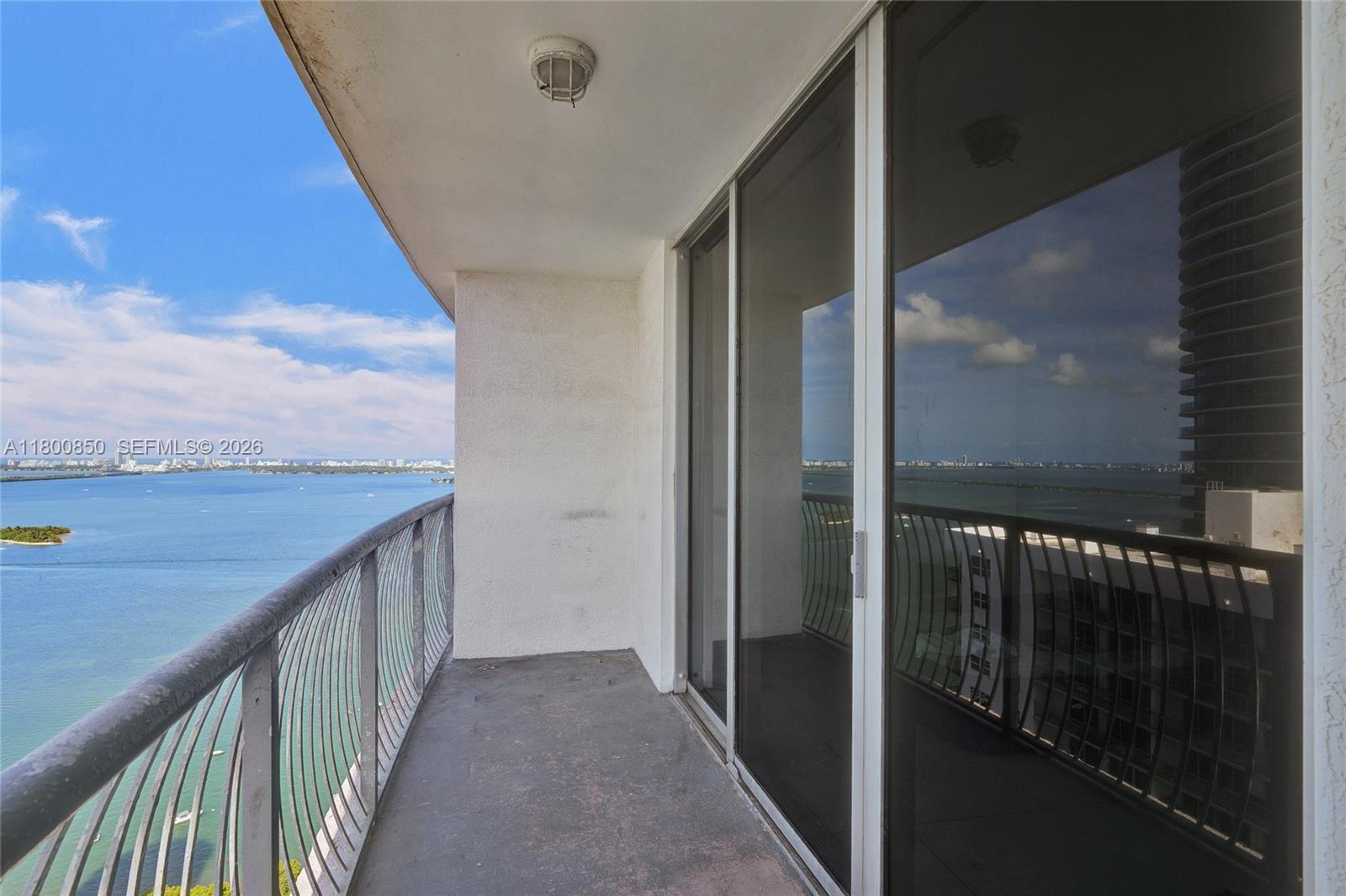 A balcony with a metal railing overlooks a large body of water and city skyline — 1750 N Bayshore Dr # 4007, Miami FL 33132, MIAMI, FL