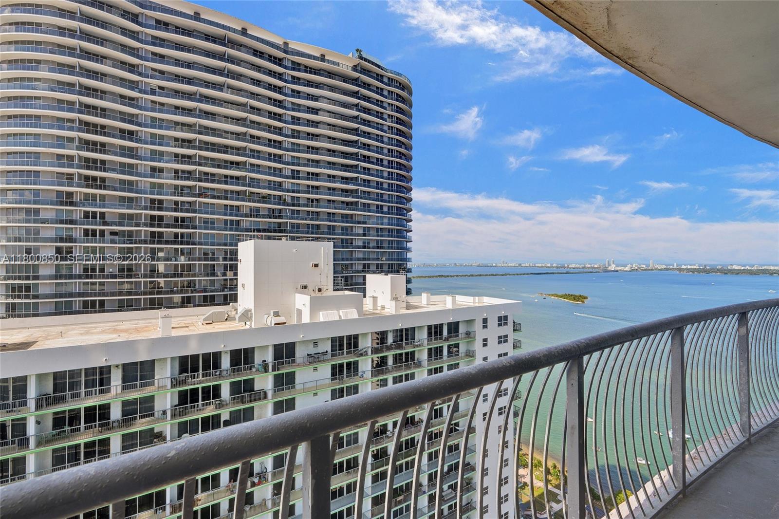 A balcony view overlooks a large white apartment building and a body of water — 1750 N Bayshore Dr # 4007, Miami FL 33132, MIAMI, FL