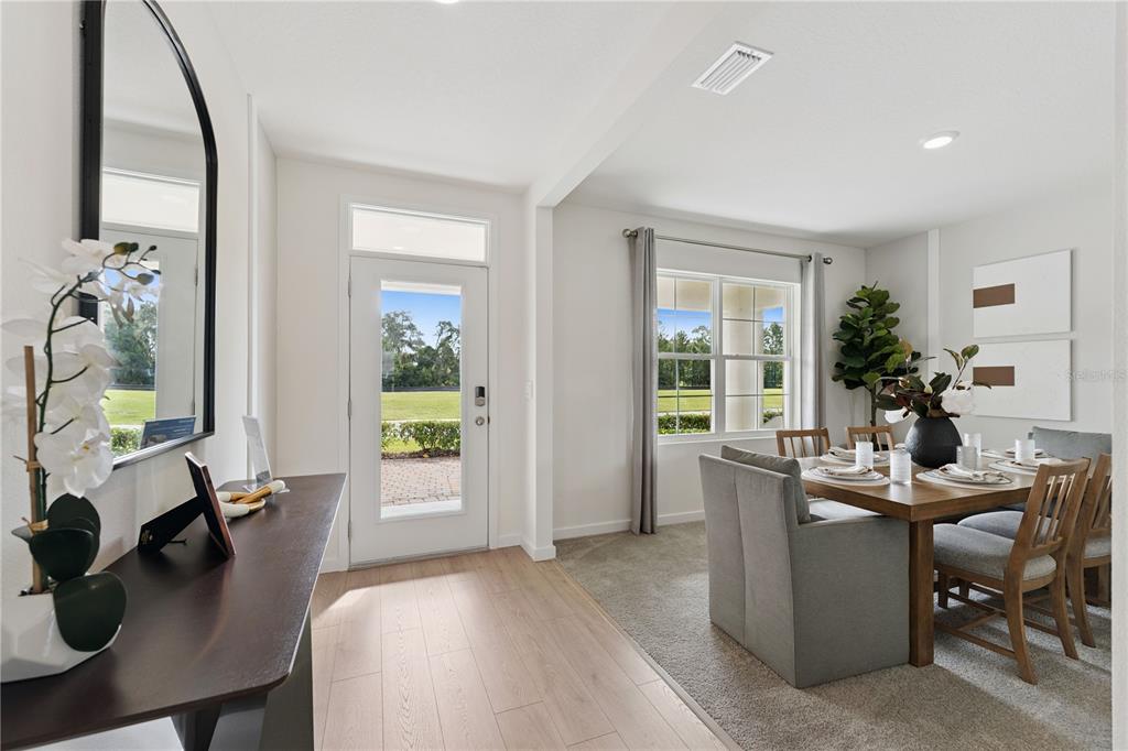 A dining area with a wooden table and chairs sits next to a glass-paneled door — 1132 HUDSON HARBOR LANE, KISSIMMEE, FL