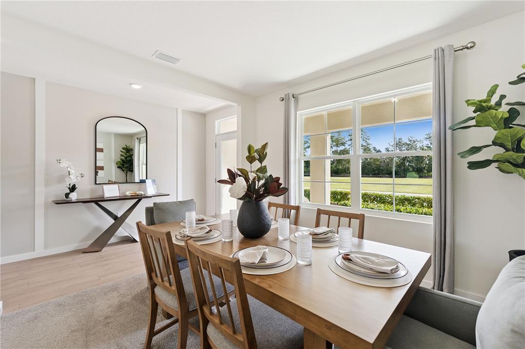 A dining room features a wooden table, upholstered chairs, a console table, and large windows — 1132 HUDSON HARBOR LANE, KISSIMMEE, FL