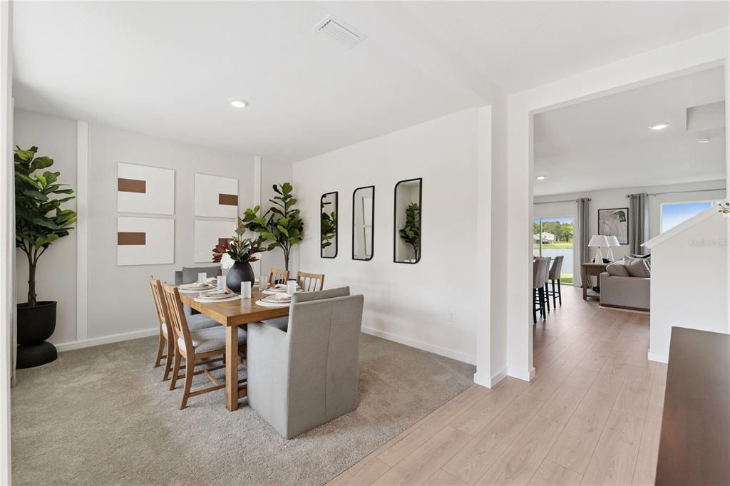 A dining room with a wooden table and gray chairs sits beside a living area — 1132 HUDSON HARBOR LANE, KISSIMMEE, FL