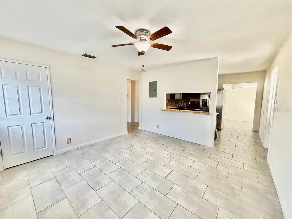 A room with light-colored tile flooring, a ceiling fan, and a kitchen pass-through window — 4109 W WALLACE AVENUE, TAMPA, FL