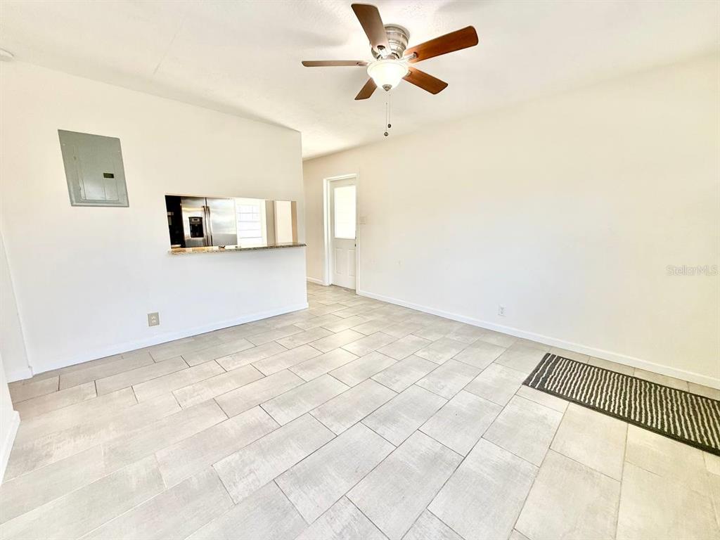 An interior view of a room with light tile flooring, a ceiling fan, and a pass-through — 4109 W WALLACE AVENUE, TAMPA, FL