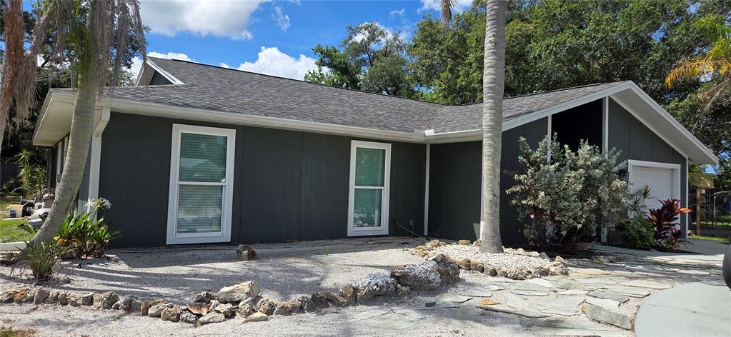 A single-story house with dark gray siding, a shingled roof, and a stone-paved front yard — 221 DADE AVENUE, SARASOTA, FL