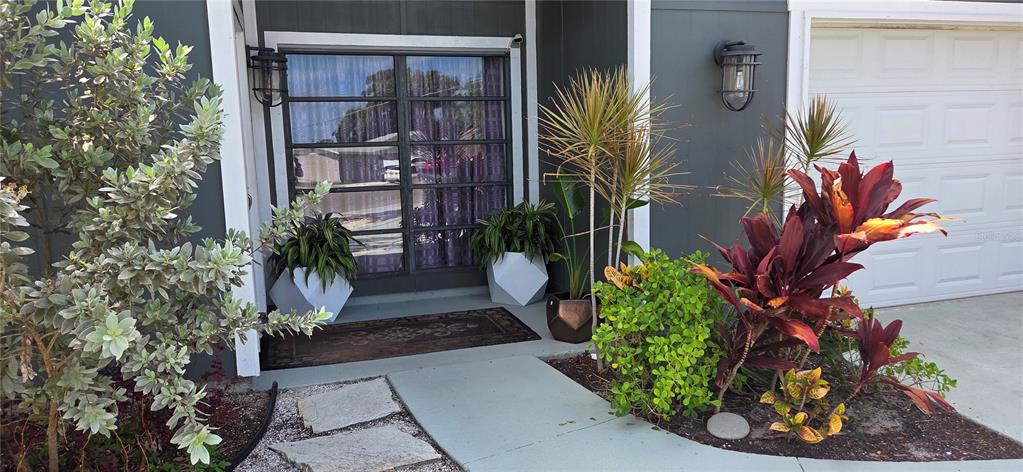 The exterior of a home features a dark-painted entrance with potted plants and landscaping — 221 DADE AVENUE, SARASOTA, FL