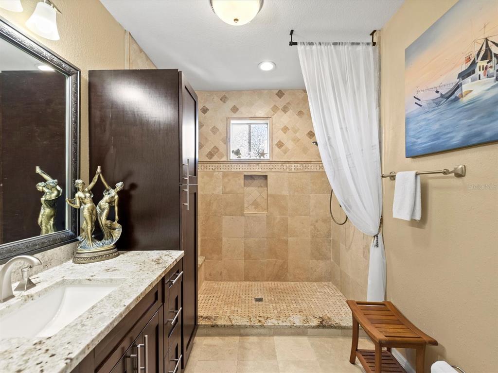 A kitchen with dark wood cabinets, granite countertops, and stainless steel appliances overlooks a living area — 5000 CULBREATH KEY WAY UNIT 9-301, TAMPA, FL