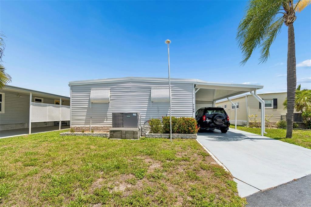 A light-colored mobile home features a carport, a driveway, and a small front lawn — 7186 MOUNT ARLINGTON DRIVE NE UNIT 421, ST PETERSBURG, FL