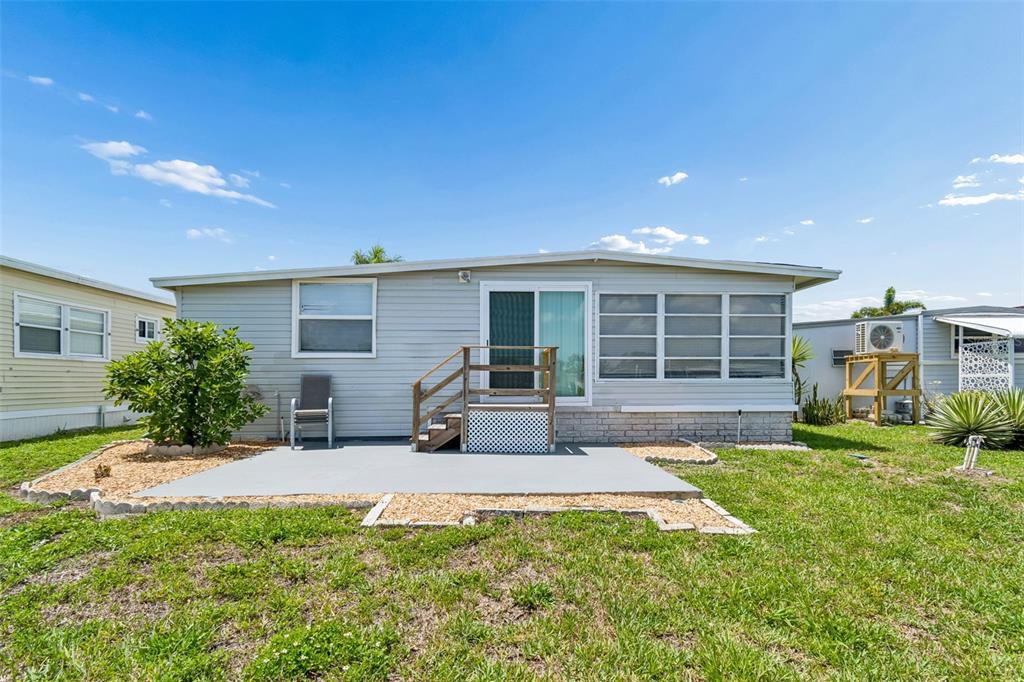 The exterior of a light-gray mobile home features a concrete patio and wooden stairs — 7186 MOUNT ARLINGTON DRIVE NE UNIT 421, ST PETERSBURG, FL