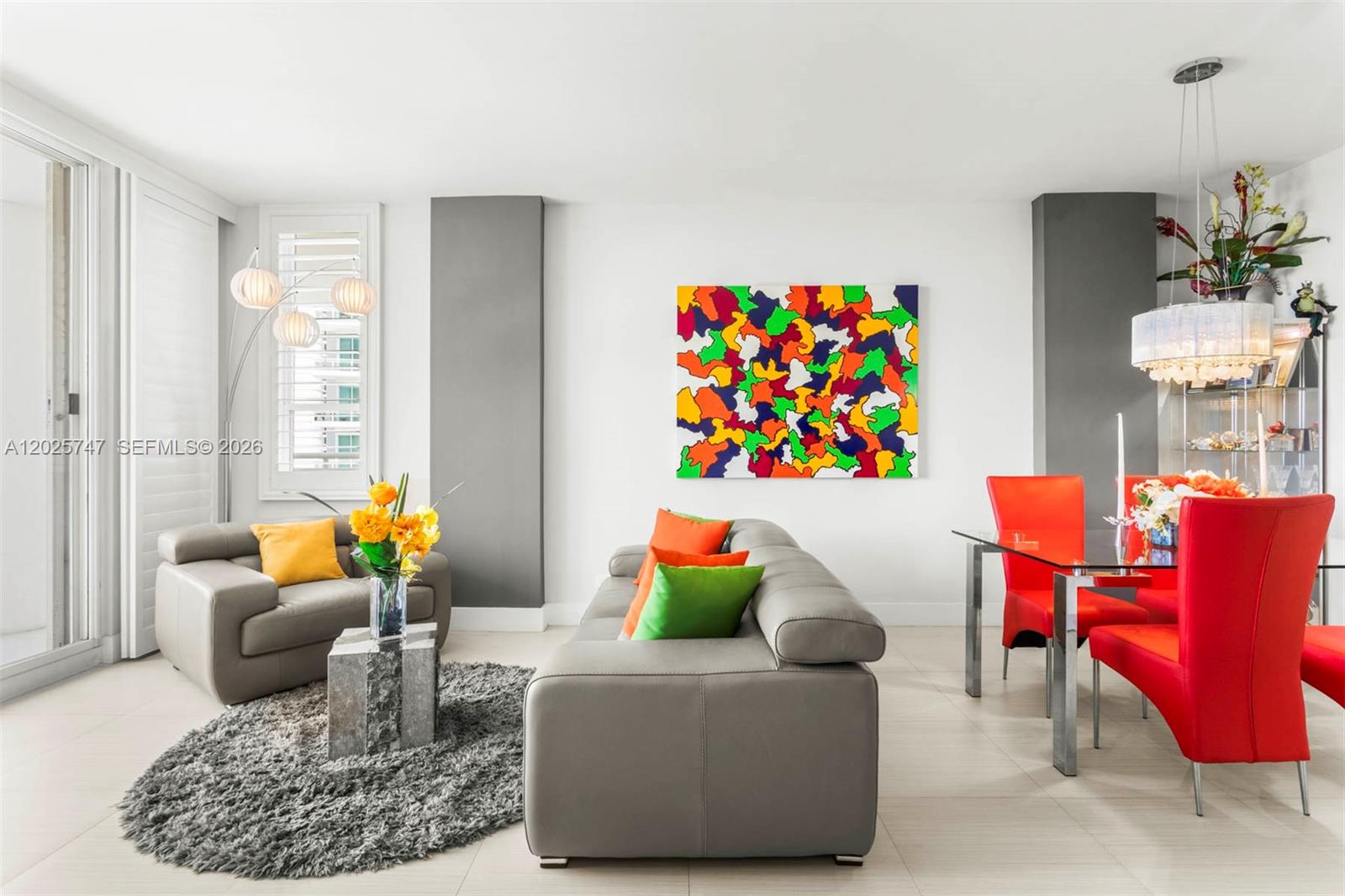 A modern living and dining area features gray leather furniture, colorful accents, and tile flooring — 888 Brickell Key Dr # 1002, Miami FL 33131, MIAMI, FL