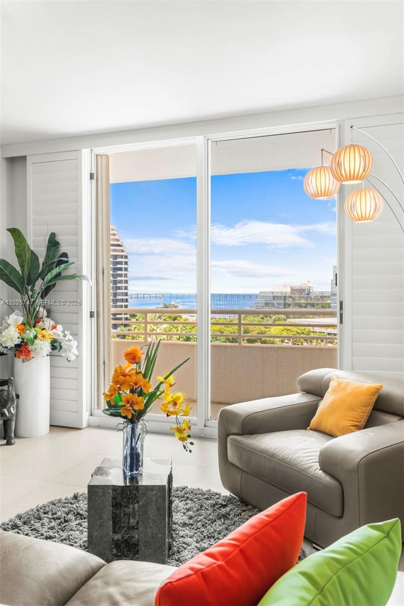 A living room features a gray armchair, a floor lamp, and a balcony with ocean views — 888 Brickell Key Dr # 1002, Miami FL 33131, MIAMI, FL