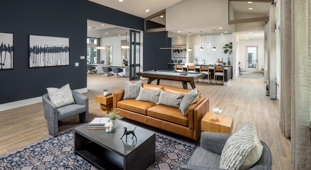 A modern lounge area features a leather sofa, pool table, and gray armchairs on tile floors — 10881 CALADESI AVENUE UNIT A2, TAMPA, FL