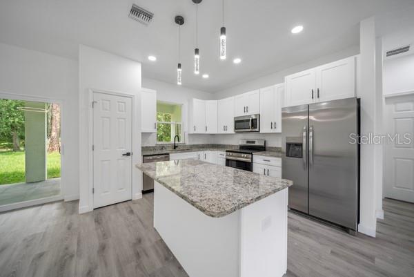 A modern kitchen features white cabinets, granite countertops, a center island, and stainless steel appliances — 3908 GARIENDA AVENUE, SEBRING, FL