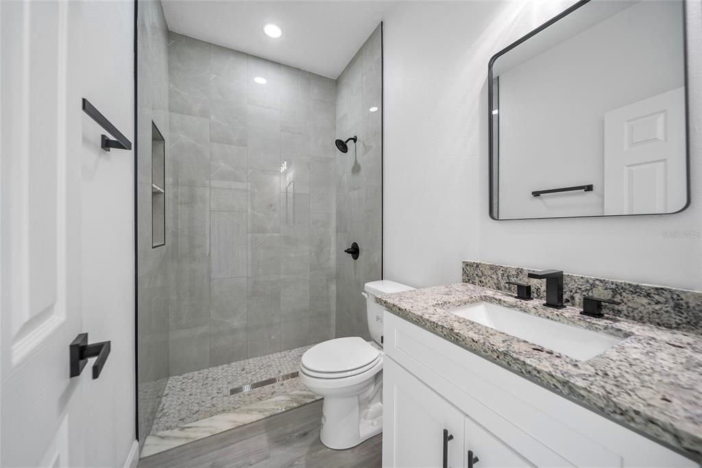 A bathroom features a walk-in shower with gray tile, a white vanity, and a toilet — 3908 GARIENDA AVENUE, SEBRING, FL