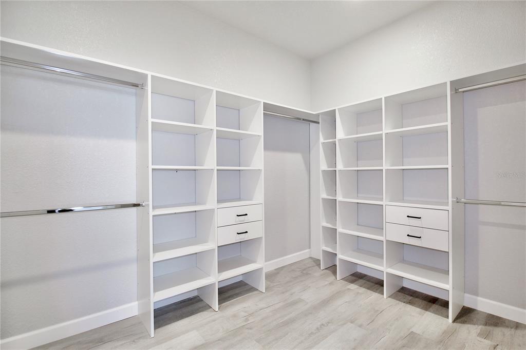 A walk-in closet features white shelving units, hanging rods, and light wood-look flooring — 3908 GARIENDA AVENUE, SEBRING, FL