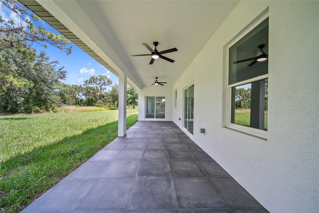A covered patio features large gray floor tiles, two ceiling fans, and sliding glass doors — 3908 GARIENDA AVENUE, SEBRING, FL