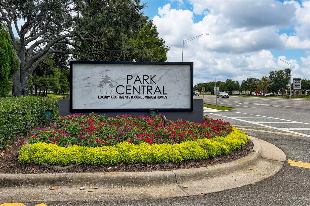 A sign for Park Central luxury apartments stands in a landscaped garden beside a road — 5017 CITY STREET UNIT 1938, ORLANDO, FL