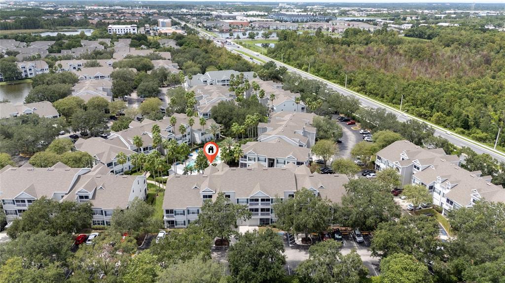 An aerial view shows a multi-story apartment complex with a pool and surrounding parking — 5017 CITY STREET UNIT 1938, ORLANDO, FL