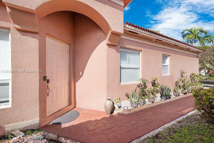 A peach-colored house exterior features a front door, arched entryway, and a brick walkway — 2327 NE 37th Ter, Homestead FL 33033, HOMESTEAD, FL