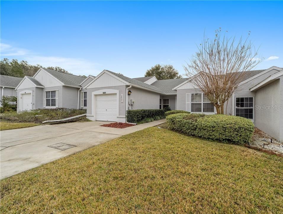 A single-story house exterior features a gray facade, a white garage door, and a lawn — 2437 SW 20TH COURT, OCALA, FL