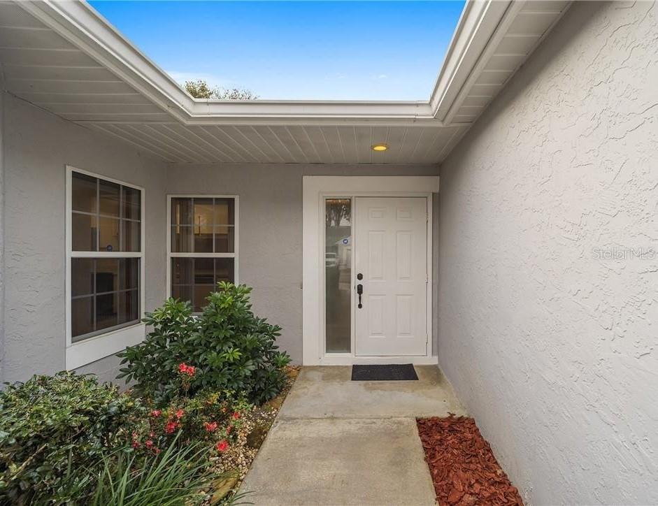 The exterior entryway features a white front door, a concrete walkway, and a small garden — 2437 SW 20TH COURT, OCALA, FL